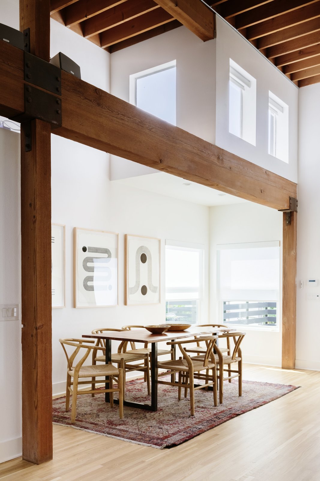 a dining nook is framed by timber beams running above the space the sunny corner is illuminated by an additional grouping of clerestory windows