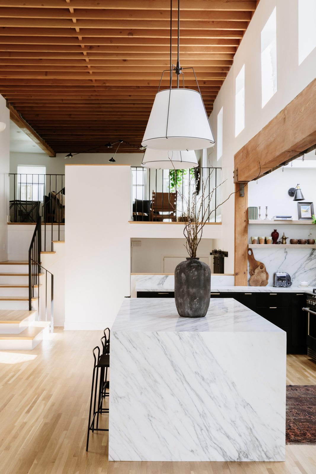 a soaring wood beamed atrium is an unexpected surprise upon entering the home the renovated kitchen features a large marble island that visually grounds the space