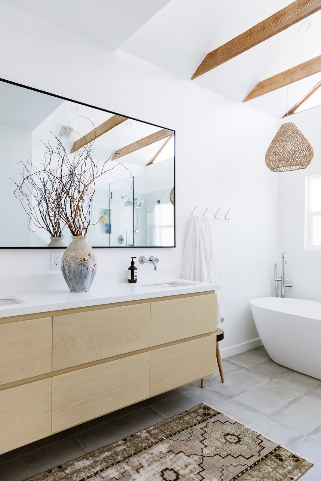 in the renovated master bathroom the couple opted for a natural wood vanity to complement the beams overhead a cool white color palette creates a serene atmosphere